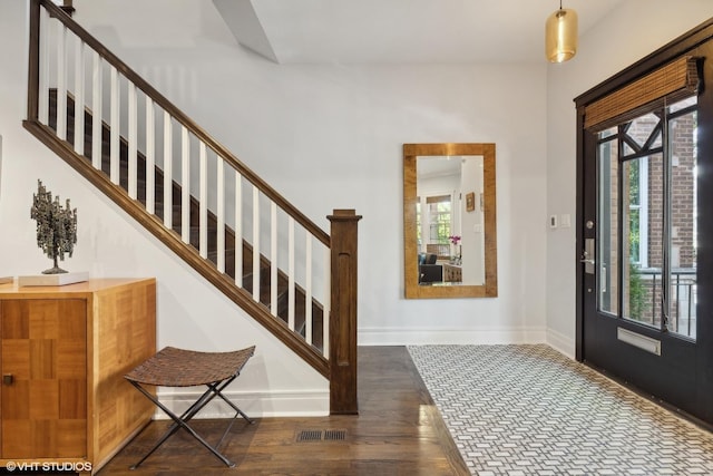 foyer entrance with visible vents, baseboards, wood finished floors, and stairway