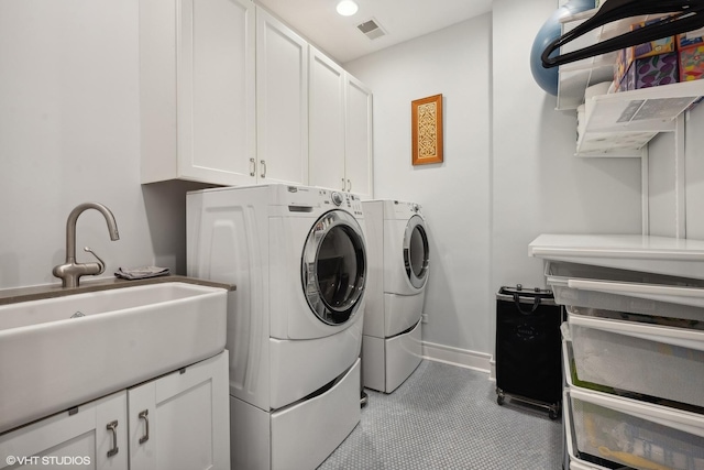 washroom with visible vents, washer and dryer, a sink, cabinet space, and baseboards