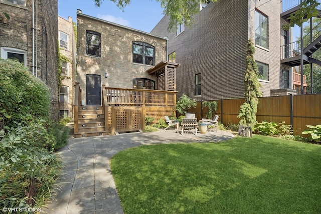 back of property with a patio area, brick siding, a lawn, and fence