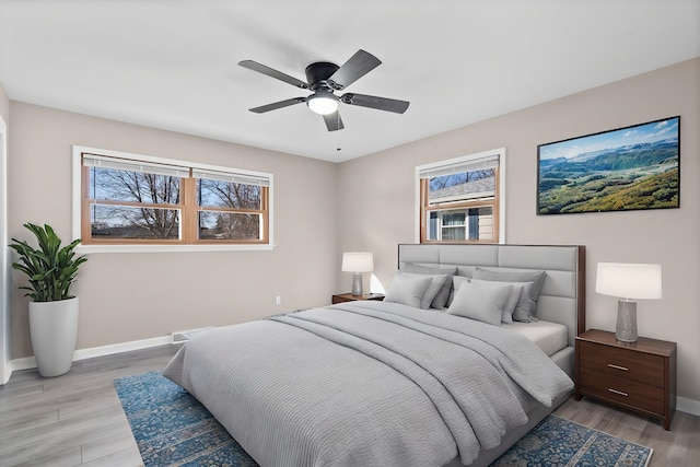 bedroom with light wood-type flooring, baseboards, and a ceiling fan