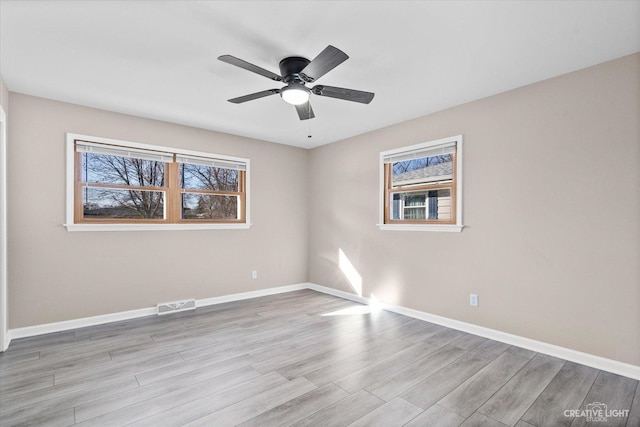 spare room with light wood-type flooring, visible vents, baseboards, and ceiling fan