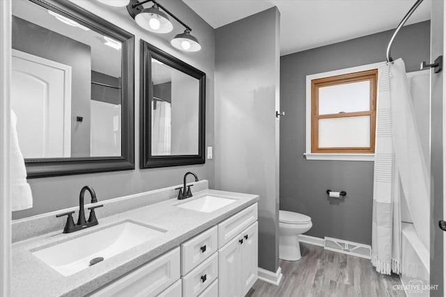 bathroom featuring visible vents, toilet, baseboards, and a sink