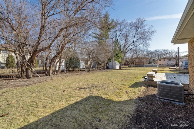 view of yard featuring an outbuilding, a storage unit, central AC, and fence