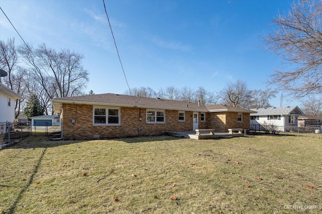 rear view of house with a yard, fence, and brick siding