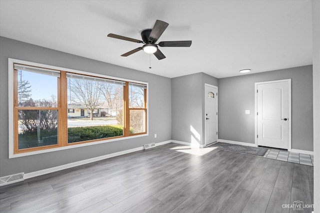 unfurnished living room with visible vents, baseboards, wood finished floors, and a ceiling fan