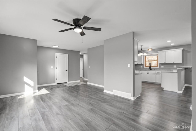 unfurnished living room featuring dark wood-style floors, visible vents, and baseboards