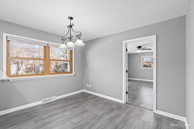 unfurnished room featuring visible vents, baseboards, and wood finished floors