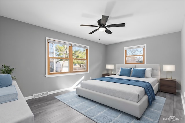 bedroom with visible vents, baseboards, wood finished floors, and a ceiling fan