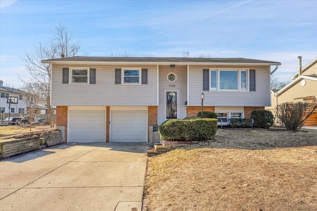 raised ranch with brick siding, a garage, and driveway