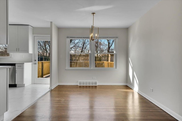 unfurnished dining area with wood finished floors, visible vents, and baseboards