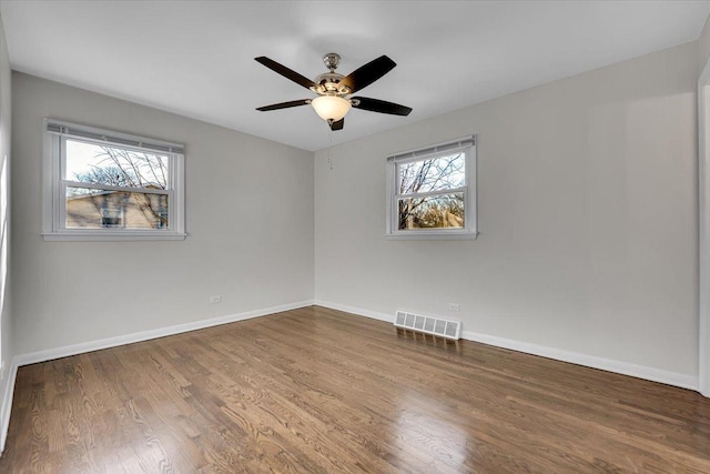 spare room featuring visible vents, a ceiling fan, baseboards, and wood finished floors