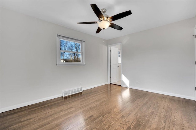 spare room with ceiling fan, visible vents, baseboards, and wood finished floors