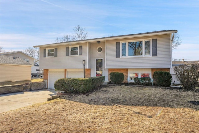 raised ranch featuring driveway, brick siding, and an attached garage