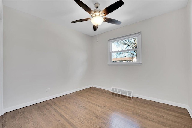 empty room featuring ceiling fan, wood finished floors, visible vents, and baseboards