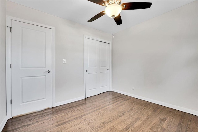 unfurnished bedroom featuring a closet, baseboards, and wood finished floors