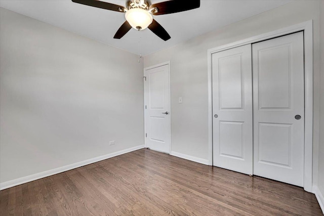 unfurnished bedroom with a closet, baseboards, wood finished floors, and a ceiling fan