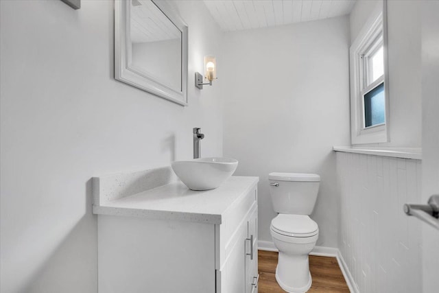 bathroom featuring vanity, toilet, wood finished floors, and baseboards