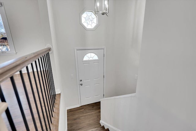 entryway featuring a high ceiling, a notable chandelier, wood finished floors, and baseboards