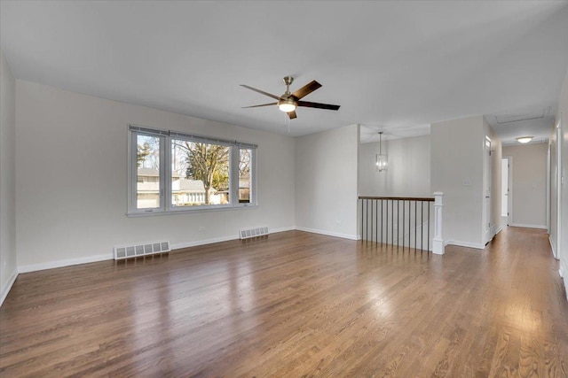 empty room with visible vents, ceiling fan, baseboards, and wood finished floors