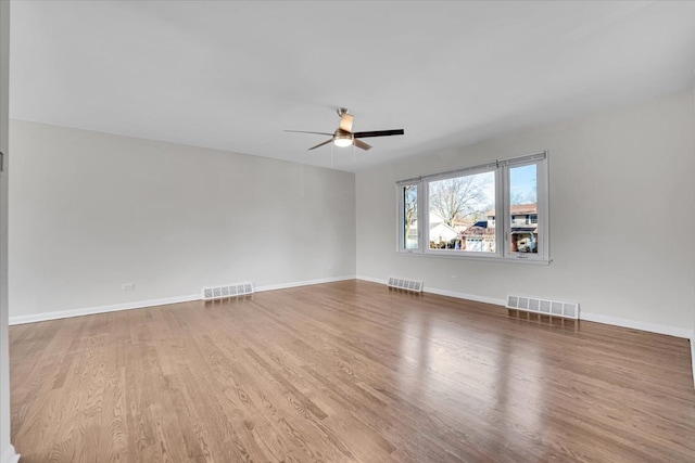 empty room with visible vents, a ceiling fan, and wood finished floors