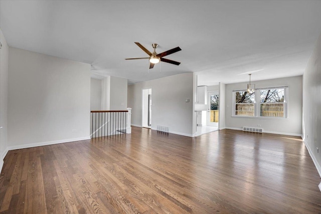 unfurnished living room with visible vents, baseboards, wood finished floors, and ceiling fan with notable chandelier