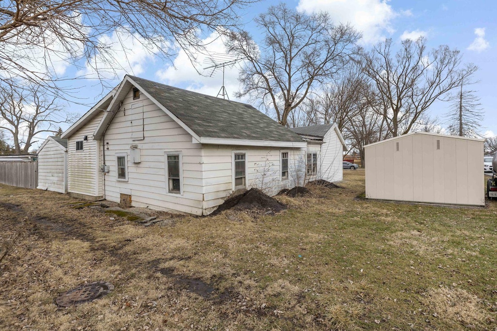 rear view of house with a lawn and an outdoor structure