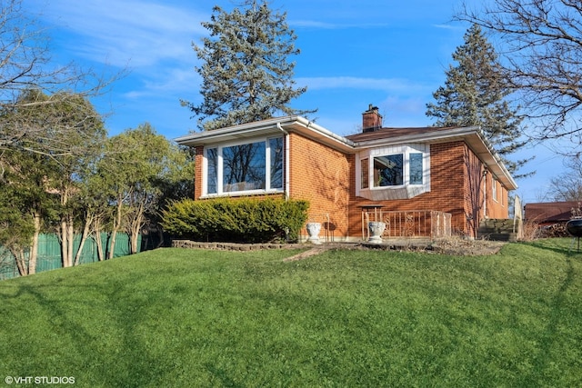 view of front of house with brick siding, a chimney, and a front yard