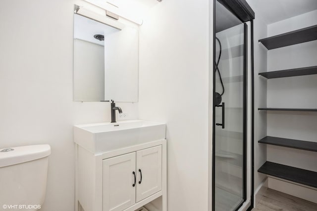 bathroom with vanity, a shower stall, toilet, and wood finished floors