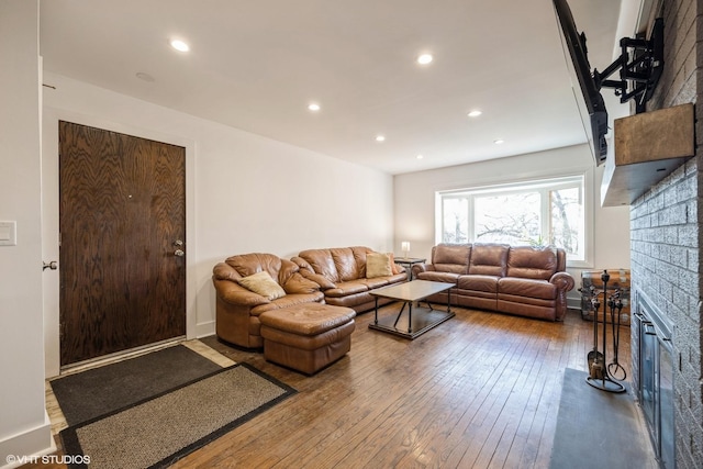 living room with a glass covered fireplace, recessed lighting, and wood-type flooring