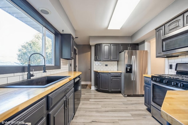 kitchen featuring a sink, appliances with stainless steel finishes, and butcher block counters