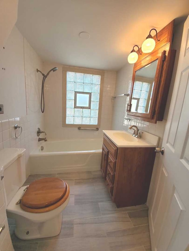 bathroom featuring toilet, tile walls, shower / washtub combination, and vanity