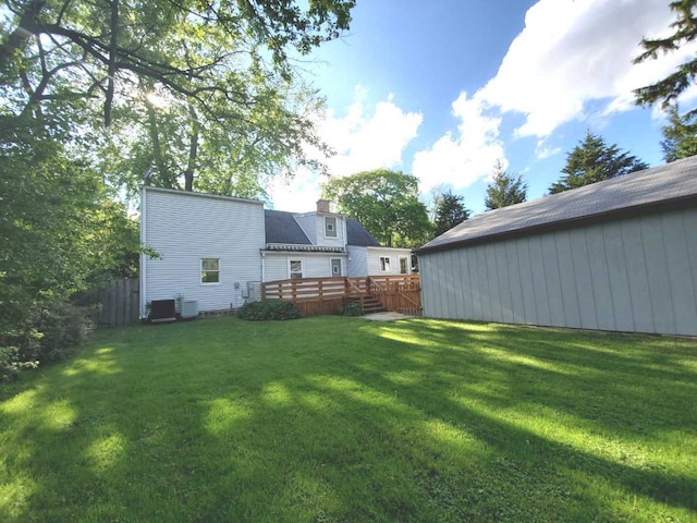 view of yard featuring central air condition unit, a deck, and fence