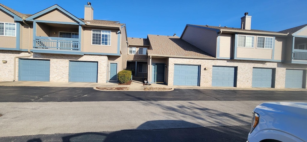 townhome / multi-family property with brick siding, a balcony, and a chimney