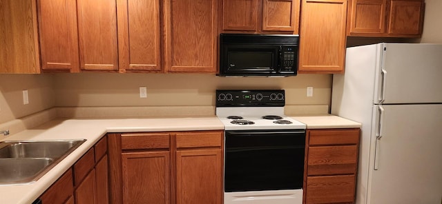 kitchen featuring black microwave, light countertops, electric range oven, freestanding refrigerator, and a sink