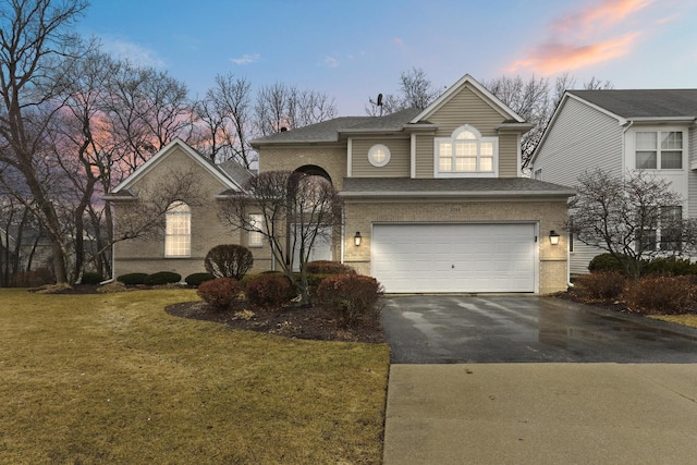 view of front of house featuring aphalt driveway, a yard, roof with shingles, a garage, and brick siding