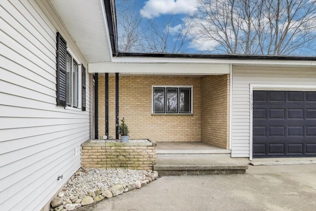 property entrance with brick siding, an attached garage, and a porch