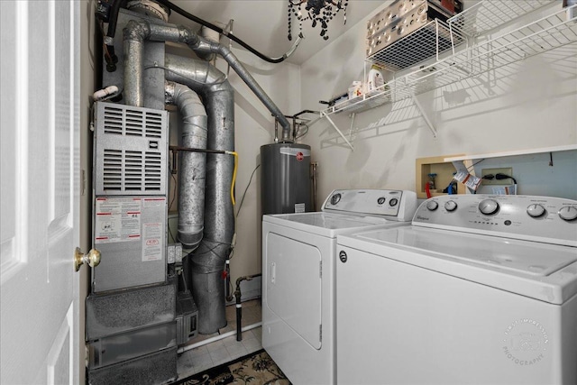 clothes washing area featuring water heater, laundry area, tile patterned floors, and separate washer and dryer