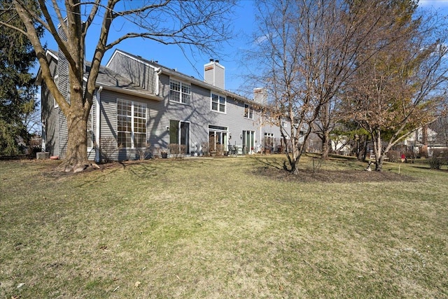 back of house with a chimney and a yard