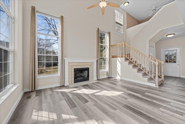 unfurnished living room featuring stairway, baseboards, and ceiling fan