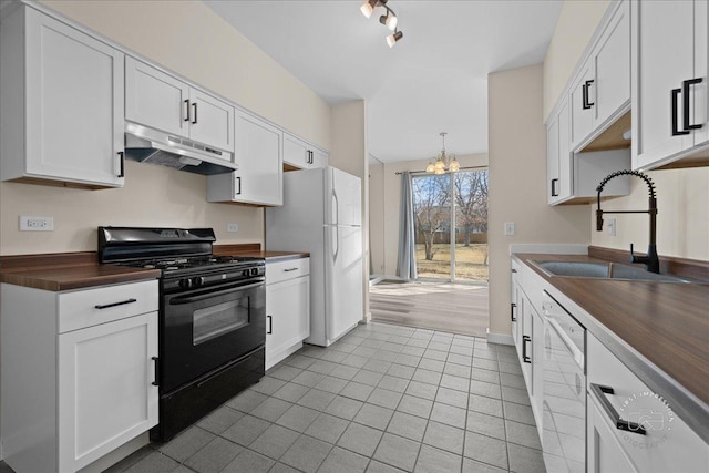 kitchen with under cabinet range hood, freestanding refrigerator, black range with gas cooktop, wood counters, and a sink