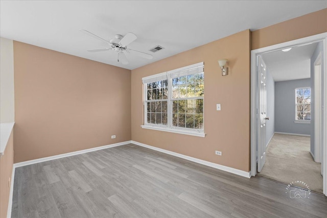 unfurnished room featuring wood finished floors, a ceiling fan, visible vents, and baseboards