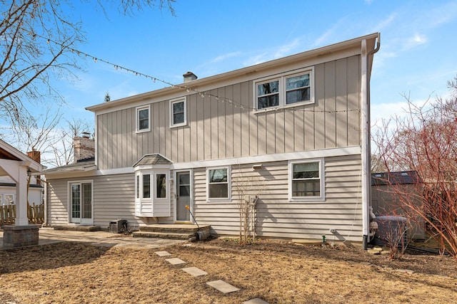 rear view of property featuring a chimney and entry steps