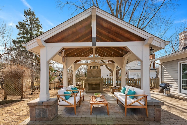 view of patio / terrace featuring a gazebo, an outdoor living space with a fireplace, fence, and grilling area