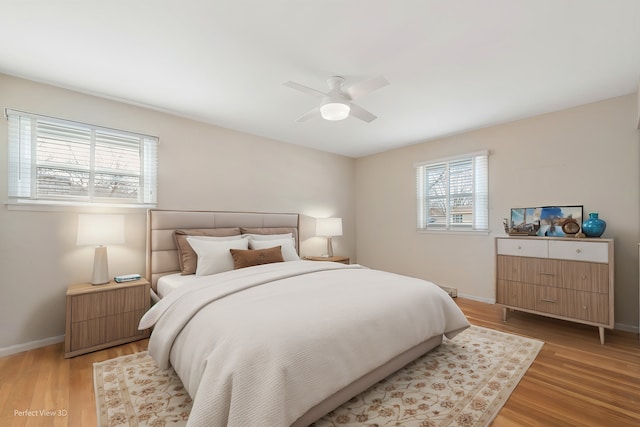 bedroom featuring multiple windows, baseboards, light wood-type flooring, and ceiling fan