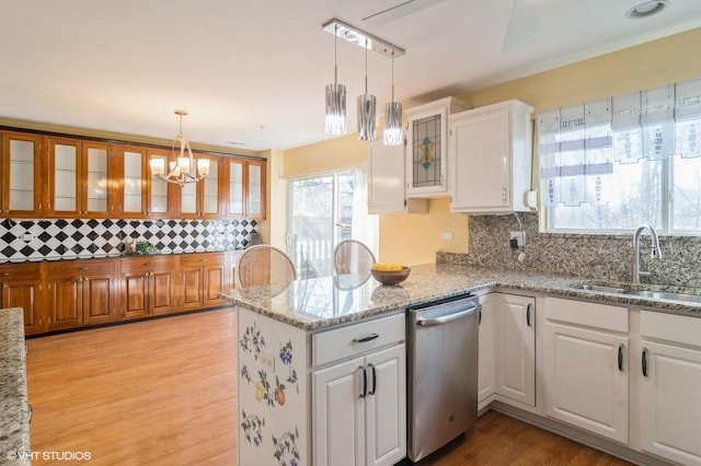 kitchen featuring a peninsula, a sink, white cabinets, glass insert cabinets, and stainless steel dishwasher