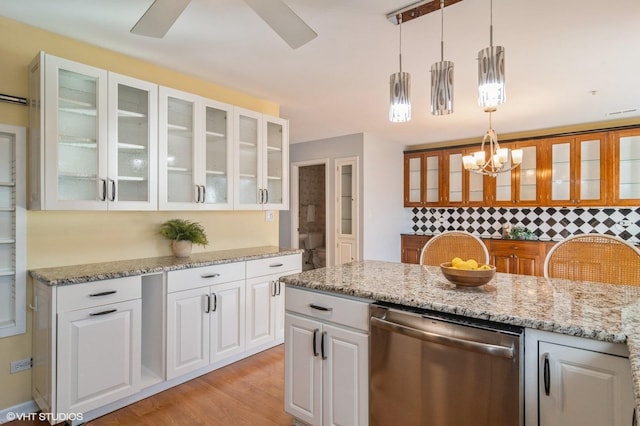 kitchen with light stone countertops, light wood-style floors, dishwasher, and white cabinetry