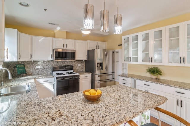 kitchen featuring tasteful backsplash, visible vents, white cabinets, stainless steel appliances, and a sink