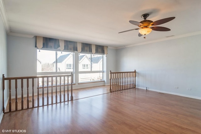 spare room with visible vents, baseboards, wood finished floors, and crown molding