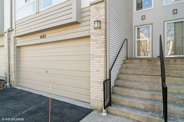 view of exterior entry featuring brick siding and driveway