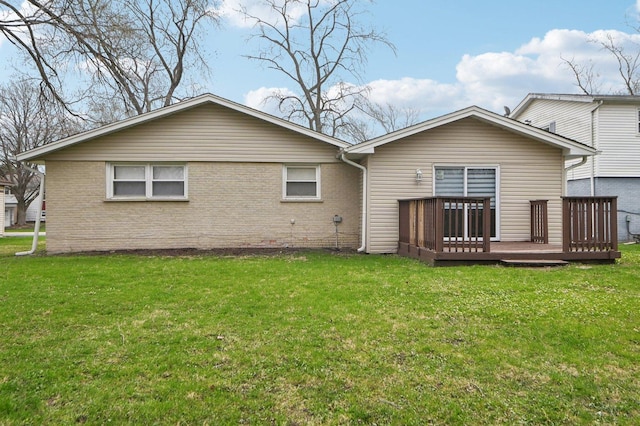 rear view of house featuring a wooden deck, brick siding, and a yard